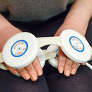 A Close-Up Of A Person Holding The Almagia International ALMAG-01 PEMF Therapy Device Over Their Hands And Lap
