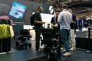 A Group Of Men Discussing The STRUTT ev1 Smart Electric Mobility Vehicle Shown In A Convention Center Setting