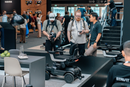 A Wide Shot Of Three Photographers Standing Near The STRUTT ev1 Smart Electric Mobility Vehicle Shown In A Convention Center Setting