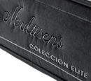 Close-Up View Of A Dark Gray Plush Fabric Surface With Embroidered Text Reading 'Multisens' And 'Coleccion Elite' In Light Gray Thread