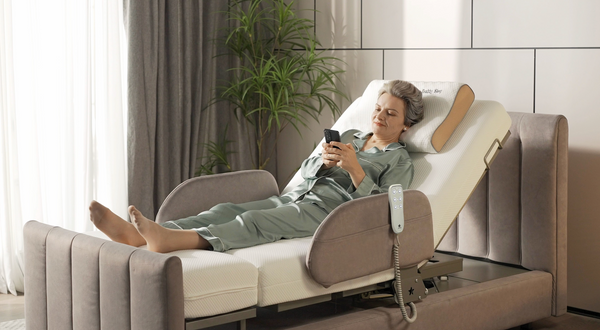 Close Up Left Side View Of An Elderly Woman Lying In The StarSleep Arlo Rotating Bed Using Her Phone With The Head Section Elevated In A Bedroom Setting