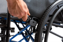 Close Up View Of A Hand Adjusting The Wheel Lock Mechanism Of The Strongback ErgoSteel Wheelchair
