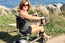 Vista de cerca de una mujer conduciendo el scooter de movilidad liviano de viaje SmartScoot con una férula en la pierna, en un entorno al aire libre