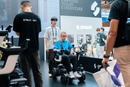 Close Up View Of A Young Boy Riding In The STRUTT ev1 Smart Electric Mobility Vehicle With An Employee Standing Behind Him Shown In A Convention Center Setting