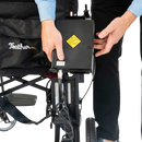 Close Up View Of The Feather Electric Wheelchair Shown With Person Holding The Battery
