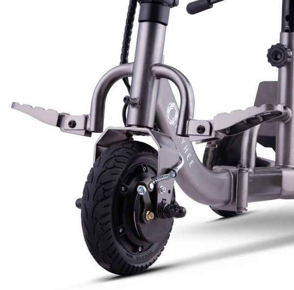 Close Up View Of The Front Wheel And Footrests For The Reyhee Triad Compact Folding Electric Mobility Scooter Shown With The Gun Metal Colored Frame