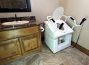 Close Up View Of The Throne Buttler Powered Toilet Lift Chair With Base Bidet Seat TLFE003 Shown In The Raised Position Over A White Toilet Bowl In A Bathroom Setting