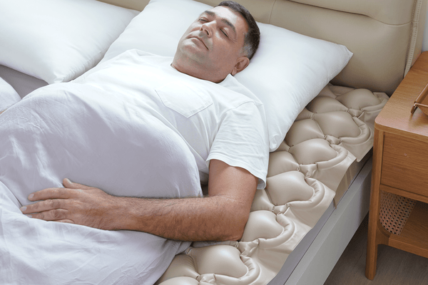 Close Up View Of The Wellell Domus 1 Alternating Pressure Redistribution Mattress Shown With A Patient Lying On The Mattress In A Home Care Setting