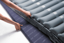 Close Up View Of The Wellell Domus 3 Alternating Pressure Redistribution Mattress System With Quilted Cover Shown With Two Hands Adjusting The Mattress