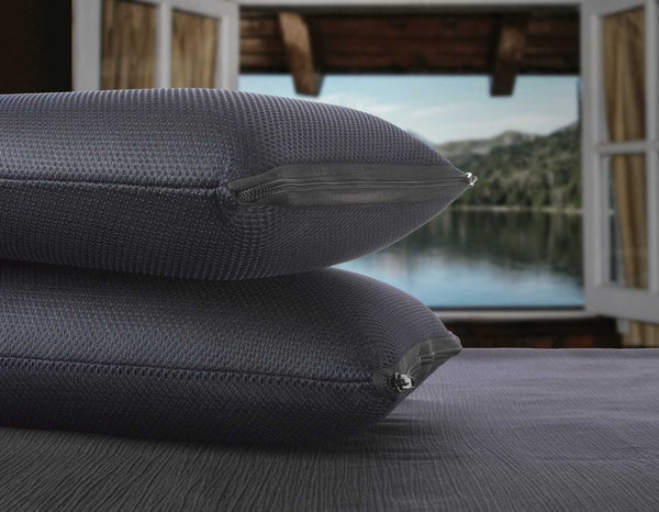 Close Up View Of Two Of The Eurolux Memory Restore Travel Pillows Stacked On Each Other With A Lake Shown In The Background In A Cabin Setting