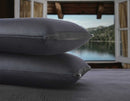 Close Up View Of Two Of The Eurolux Memory Restore Travel Pillows Stacked On Each Other With A Lake Shown In The Background In A Cabin Setting