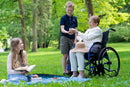 Elderly Woman Sitting In The Strongback 24 Ultra-Lightweight Wheelchair With Two Children In A Park Setting