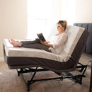 Flexabed Hi Low Adjustable Bed A person sitting on an adjustable hospital bed with gray bedding, reading a book.