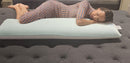 Front Centered View Of A Woman Wearing A Dress Lying On The Standard Body Eurolux Green Planet Pillow Shown In A Showroom Setting