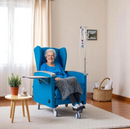 Front Centered View Of An Elderly Woman Sitting In The Nitrocare Aura 911 Chemotherapy Recliner Chair Shown In A Medical Setting