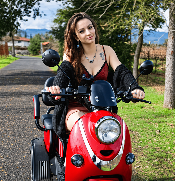 Front Centered View Of The Pushpak Motors- Pushpak 1000 Two- Person Electric Scooter In The Red Color Shown With A Woman Riding In The Countryside