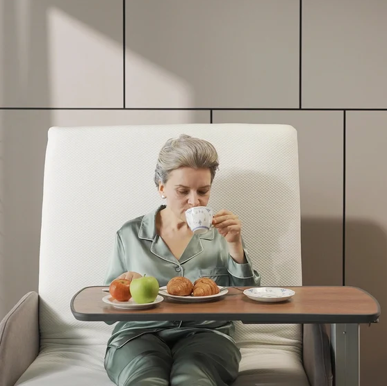 Front Close Up View Of A Woman Using The StarSleep Overbed Table For Drinking And Eating While Sitting On The StarSleep Arlo Rotating Bed Shown In A Bedroom Setting