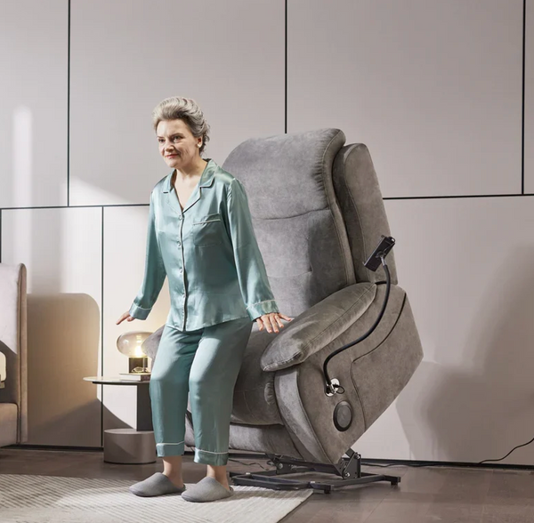 Front Left Side View Of An Elderly Woman Rising Out Of The StarSleep Starise Massage Lift Chair Shown In The Lifted Position In A Bedroom Setting