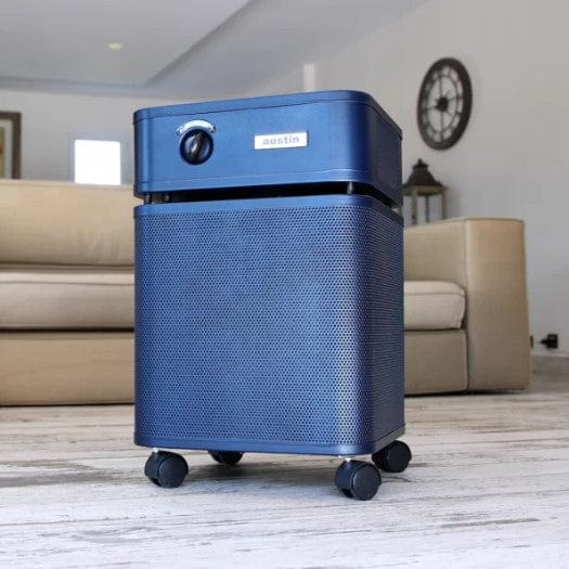 Front Left Side View Of The Austin Air Systems HealthMate Standard Air Purifier Shown In The Midnight Blue Color In A Home Setting