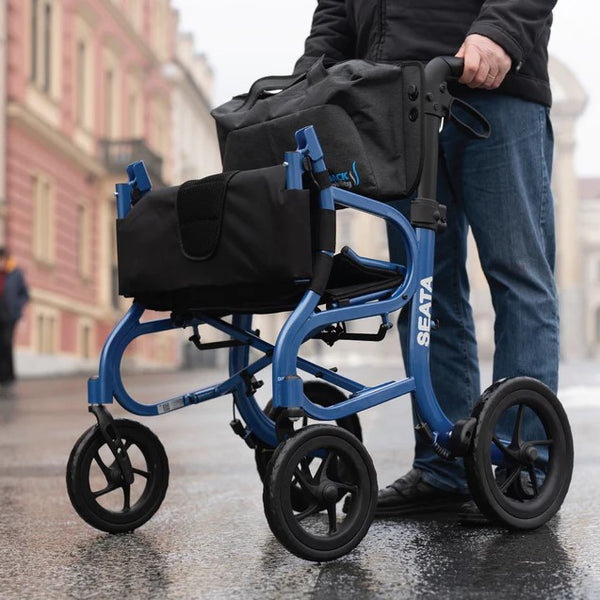 Front Left Side View Of The Strongback Mobility SEATA Rollator Shown With Elderly Man Holding The Handles In An Outdoor Setting