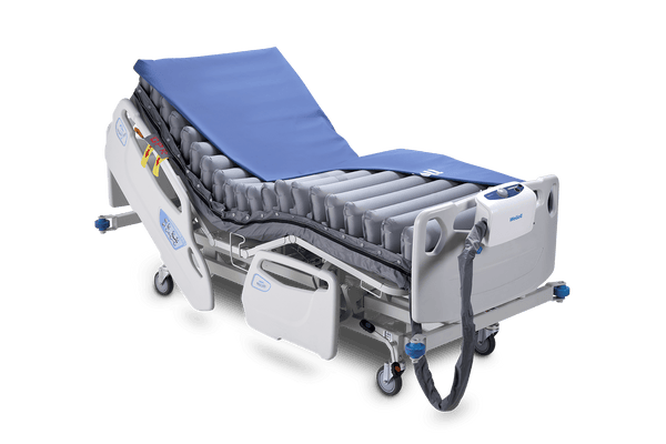 Front Left Side View Of The Wellell Domus 3 Alternating Pressure Redistribution Mattress System Shown On An Adjustable Bed With The Control Unit Hanging On The Footboard With The Cover Slightly Removed