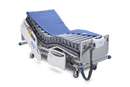 Front Left Side View Of The Wellell Domus 3 Alternating Pressure Redistribution Mattress System Shown On An Adjustable Bed With The Control Unit Hanging On The Footboard With The Cover Slightly Removed