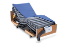 Front Left Side View Of The Wellell Domus 3 Alternating Pressure Redistribution Mattress System With Quilted Cover Shown On An Adjustable Bed With The Control Unit Hanging On The Footboard With The Cover Slightly Removed