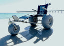 Front Left View Of The Debug Mobility EZ Roller Floating Beach Chair In A Beach Setting With A Pier In The Background