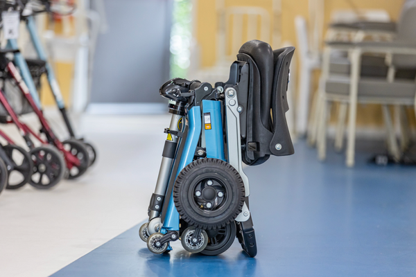 Front Right Side View Of The FreeRiderUSA Luggie Super Plus 3 Folding Mobility Scooter Shown In The Folded Upright Position In The Ocean Blue Color In An Indoor Setting