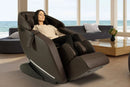 Front Right Side View Of The Kyota Genki M380 Massage Chair In Brown Color Shown In An Indoor Setting With A Woman Sitting In The Chair