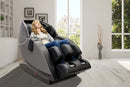 Front Right Side View Of The Kyota Kansha M878 Massage Chair In Black And Gray Color In An Indoor Setting With A Woman Sitting In The Chair