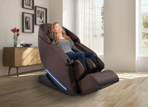 Front Right Side View Of The Kyota Yugana M780 4D Massage Chair In Brown Color Shown In An Indoor Setting With A Woman Sitting In The Chair