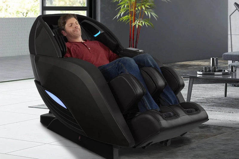Front Right Side View Of The Kyota Yutaka M898 Massage Chair Shown In The Black Color In An Indoor Setting With A Man Sitting In The Chair