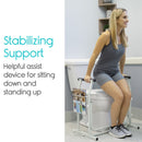 Front Right Side View Of The Vive Health Stand Alone Toilet Rail Placed Next To A Toilet Bowl With A Woman Using The Railing To Stand Up In A Bathroom Setting Demonstrating Its Stabilizing Support