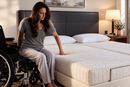 Front View Of A Woman Transferring From A Wheelchair To The Transfer Master Supernal Hi Low Adjustable Bed