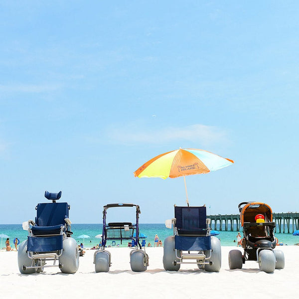 Front View Of The Debug Mobility All-Terrain Beach Wheelchair And The Other Products Offered By Debug In A Beach Setting With The Ocean In The Background