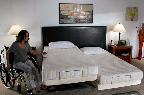 Front View Of The Transfer Master Supernal Hi Low Adjustable Bed In Split King Size With Woman In Wheelchair Using The Remote To Elevate The Bed