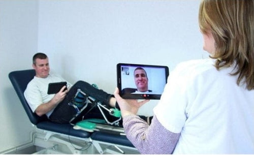 Kinetec Spectra Kompanion Knee CPM Machine In A Clinic Setting With Patient Using Device While Doctor Treats