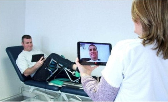 Kinetec Spectra Kompanion Knee CPM Machine In A Clinic Setting With Patient Using Device While Doctor Treats