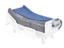 Left Side View Of An Adjustable Hospital Bed With The Wellell Optima Turn Lateral Rotation Pressure Relief Mattress With Stretch Cover On It, White Side Rails, And A Digital Control Unit On The Footboard