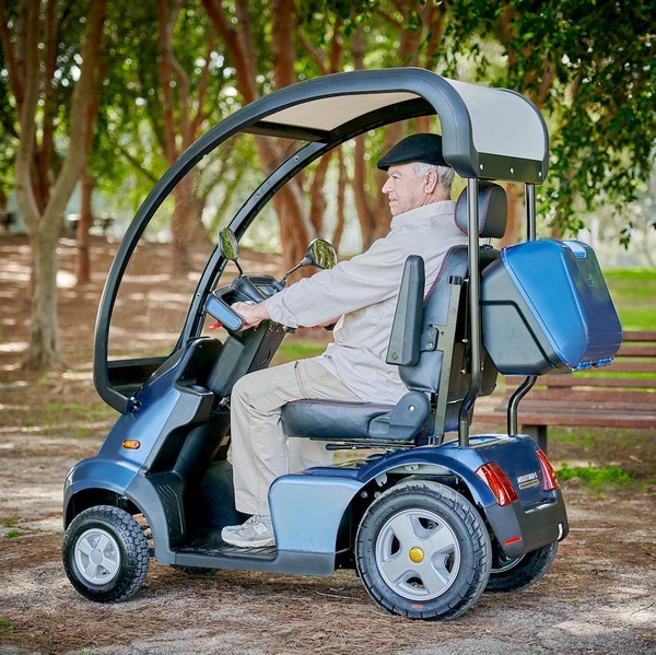 Left Side View Of The AFIKIM Afiscooter S4 Scooter Shown In The Blue Color With The Optional Hard Top Canopy And Rear Lock Box In An Outdoor Setting