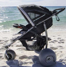 Left Side View Of The Debug Mobility Baby Bug Beach Stroller In A Beach Setting With The Ocean In The Background