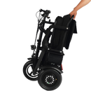 Left Side View Of The MotoTec Folding Mobility Electric Trike 48v 700w Dual Motor Lithium Shown In The Folded Position With Hand Moving The Scooter