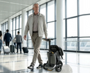 Man Dragging The Paiseec L5 Mobility Scooter In Silver Color In An Airport Terminal With Travelers And Luggage