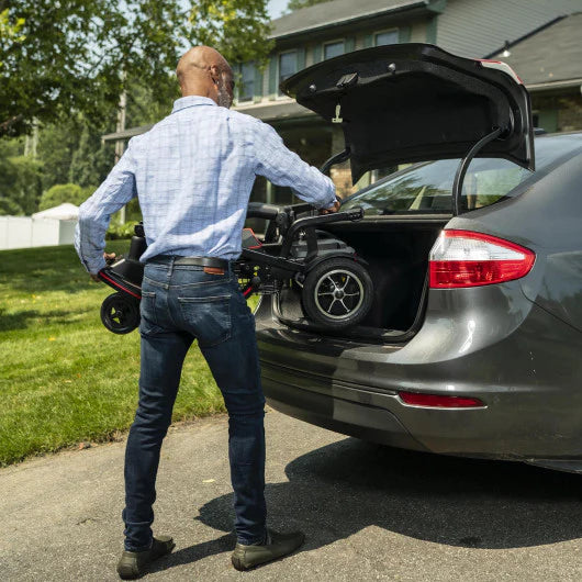 Man Loading The Feather Mobility Scooter Into The Trunk Of A Car In A Suburban Setting 