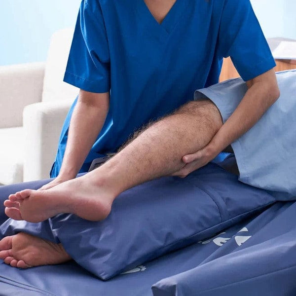 Nurse Assisting The Patient By Adjusting His Leg On The Wellell Optima Turn Lateral Rotation Pressure Relief Mattress With Stretch Cover