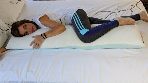 Overhead View Of A Woman In Fitness Clothing Draping Her Left Leg Over The Standard Body Pillow Eurolux Green Planet Pillow On A Mattress