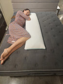 Overhead View Of A Woman Wearing A Dress Lying On The Standard Body Pillow Of The Eurolux Green Planet Pillow On A Mattress Shown In A Showroom Setting