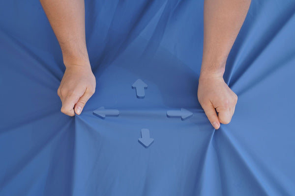 Overhead View Of The Cover Material Wellell Sedens 500 Seat Cushion With Battery Power Shown With A Healthcare Worker Stretching The Cover Highlighting Its Four Way Stretch Capability