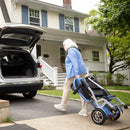 Rear View Of The Journey So Lite Mobility Scooter In The Folded Position Shown In Blue Color With Elderly Woman Rolling The Scooter Towards The Trunk Of Her Car